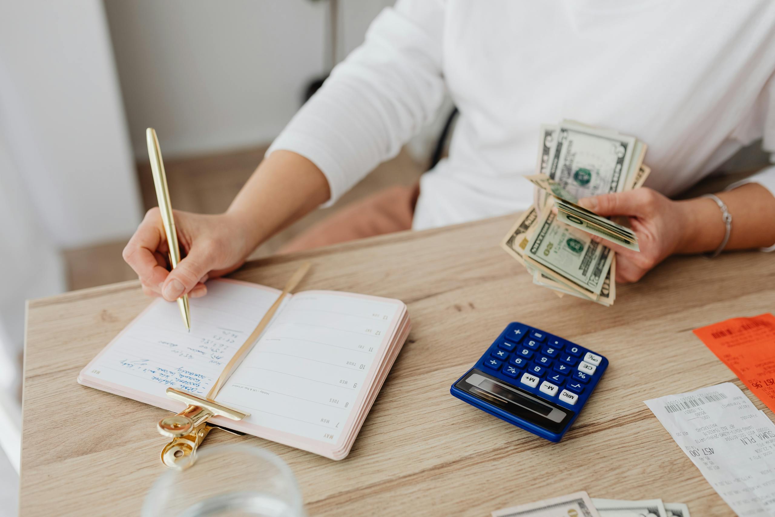 Budgeting basics – person tracking expenses with cash, calculator, and notebook
