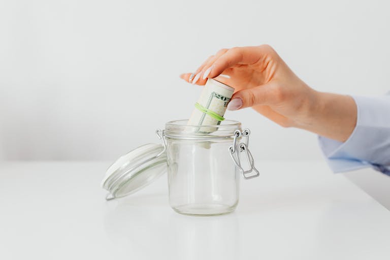 save money every month – woman placing cash in jar